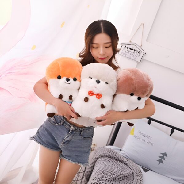 Une jeune femme souriante tenant trois peluches de chiens en peluche dans ses bras. Les peluches sont de différentes couleurs, orange, blanc et brun.