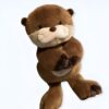 peluche-loutre-realiste-marron-2a-2 Une peluche en forme de loutre brune, debout avec les bras croisés.