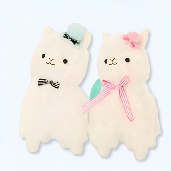 peluche-madame-lama-1a Deux peluches alpaga blanches, l'une avec un chapeau bleu et un nœud papillon noir et blanc, l'autre avec un ruban rose et un chapeau rose.