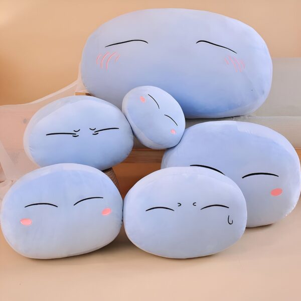 Ensemble de cinq coussins en forme de blob avec des expressions faciales différentes. Les coussins sont bleus et moelleux, parfaits pour se détendre et décorer une chambre.