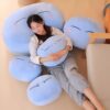 Une femme dort sur un coussin en forme de Slime. Elle est entourée de plusieurs coussins du même style.