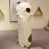 Un long coussin en forme de chat blanc avec des détails marrons, debout sur un lit.