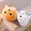 Deux coussins en forme de chat, un jaune et un blanc, posés sur un fauteuil en bois.