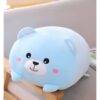 Un ours en peluche bleu clair avec un museau blanc, des yeux noirs et des joues roses, assis sur un tabouret en bois.
