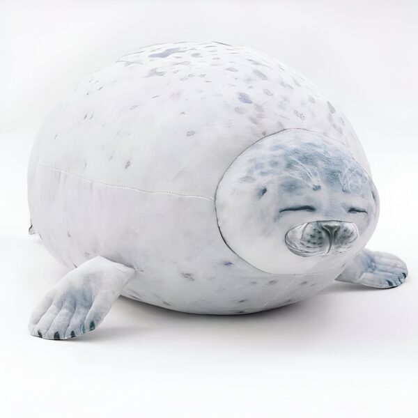 peluche-oreiller-phoque-doux-et-adorable-pour-enfant-1a-2 Une peluche de phoque gris et blanc allongé sur le ventre avec les yeux fermés.