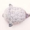 peluche-oreiller-phoque-doux-et-adorable-pour-enfant-6a-2 Un phoque gris allongé sur le dos, vu de dessus.