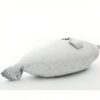 Une peluche de phoque blanc allongée sur le côté, les pattes repliées sous le corps.