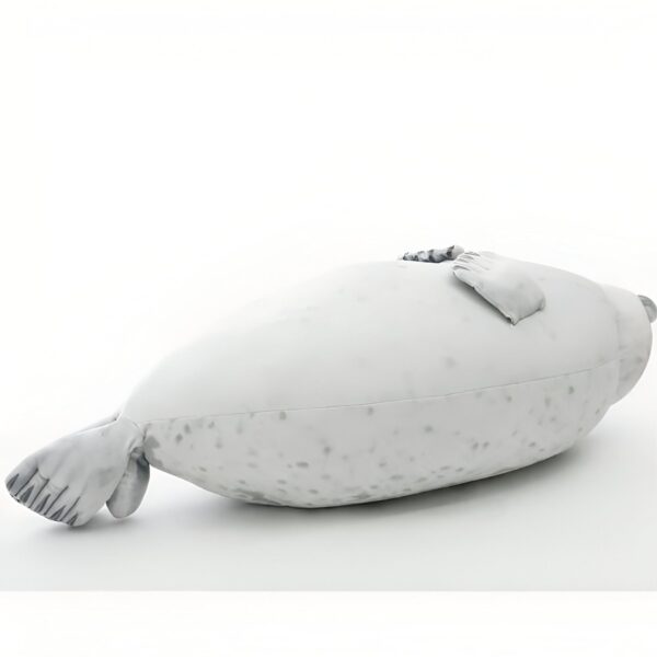 Une peluche de phoque blanc allongée sur le côté, les pattes repliées sous le corps.
