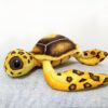 Une tortue en peluche jaune et brune avec de grands yeux noirs.