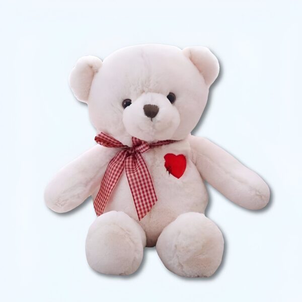 Ourson en peluche blanc avec un nœud rouge à carreaux et un cœur rouge sur la poitrine.