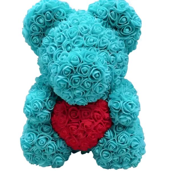Ours en peluche turquoise fait de roses artificielles tenant un cœur rouge en roses artificielles.