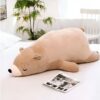 peluche-ours-marron-qui-dort-2a Un grand ours en peluche brun allongé sur un lit blanc.
