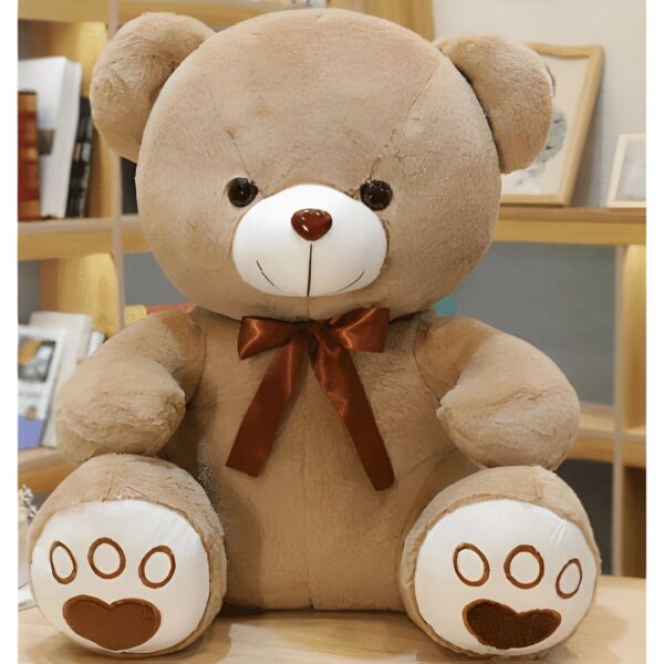 Un ours en peluche brun assis avec un nœud brun et des pattes blanches avec des empreintes de pas.