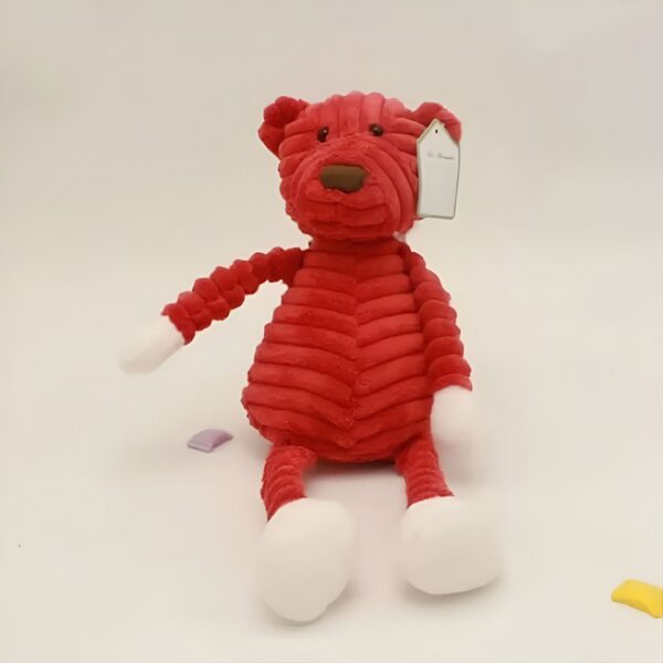 Une peluche rouge et blanche en forme d'ours avec une étiquette blanche.