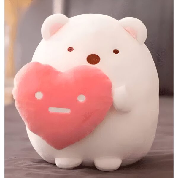 Une peluche blanche en forme d'ours tenant un cœur rose.
