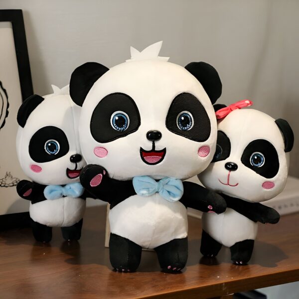 Trois adorables peluches pandas, deux avec des nœuds bleus et un avec un nœud rose, se tiennent sur une table en bois.