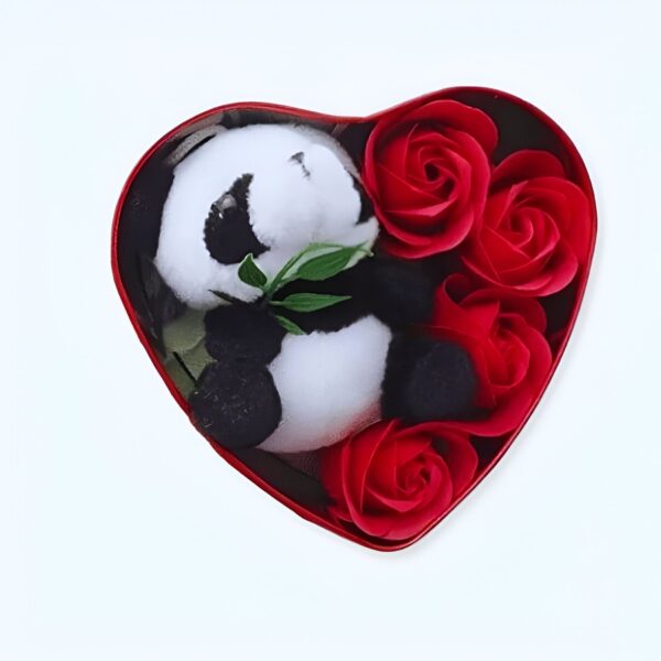 Un ours en peluche panda noir et blanc dans une boîte en forme de cœur rouge avec des roses rouges.