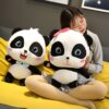 Une jeune femme assise sur un canapé jaune avec deux peluches pandas. Le panda à gauche porte un nœud papillon bleu et le panda à droite porte un nœud rose.