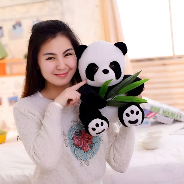 Une jeune femme souriante tenant une peluche de panda tenant du bambou.
