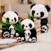 Quatre adorables peluches panda, dont deux paires de parents et leurs bébés, posent sur un tapis blanc. Ils tiennent des feuilles de bambou vertes dans leurs pattes.