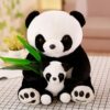 Deux peluches de panda, l'un plus grand que l'autre, assis ensemble, tenant des feuilles de bambou vertes.