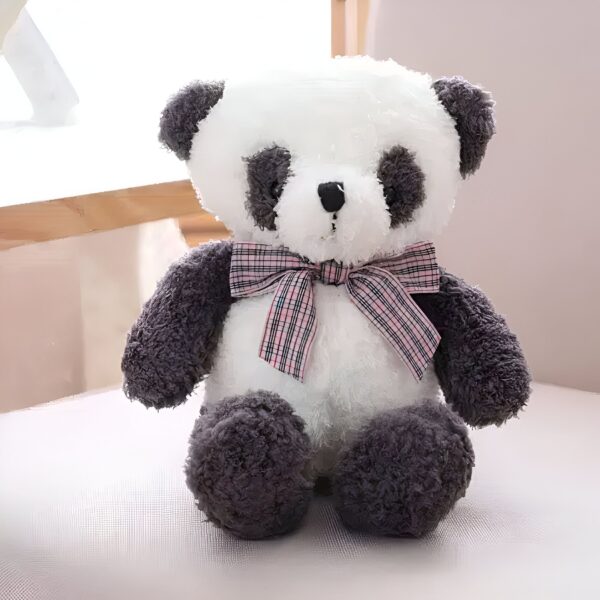 Une peluche de panda en position assise, avec un nœud rose à carreaux.
