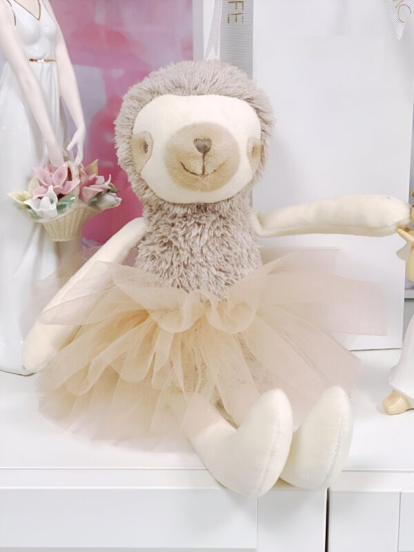 Une peluche de paresseux portant une jupe de tulle beige.