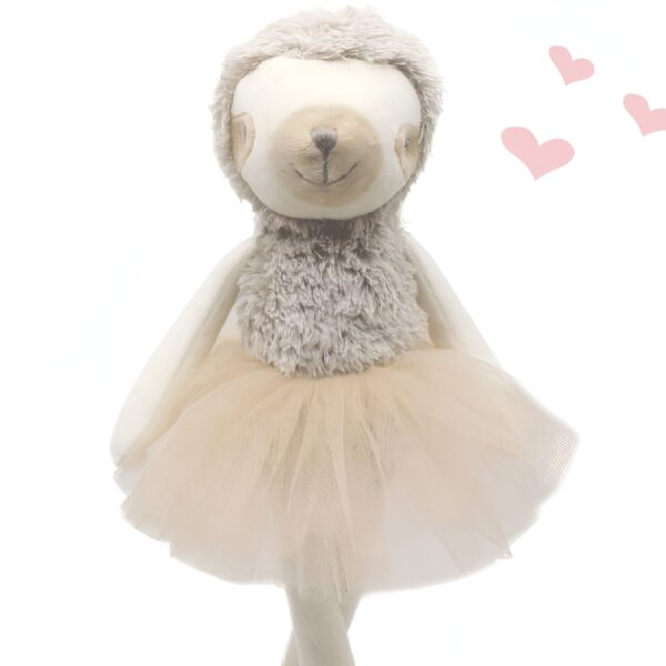 Une peluche de paresseux souriante portant une jupe tutu beige et des coeurs roses.
