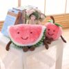 peluche-pasteque-fruit-jouet-enfant-doux-et-confortable-2a-2 Deux peluches en forme de fruits souriants : une pastèque et une pêche, posées sur une table.