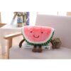 peluche-pasteque-fruit-jouet-enfant-doux-et-confortable-4a-2 Une peluche en forme de pastèque souriante assise sur un canapé.