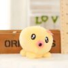 Une peluche jaune en forme de poulpe avec des yeux noirs et une bouche rose, devant une boîte en bois et un mur avec le mot "LOVE" écrit en vert.