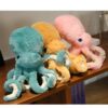 Trois adorables peluches de pieuvre en bleu turquoise, orange et rose, posées sur un comptoir en bois.