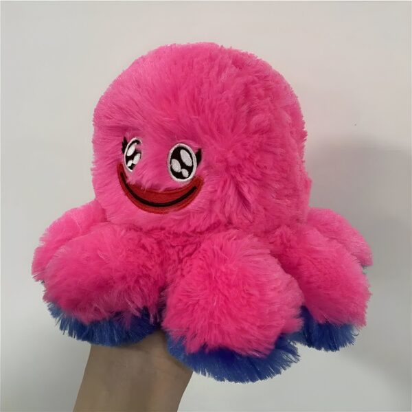 Une peluche rose en forme de pieuvre avec un visage souriant et des tentacules bleues.