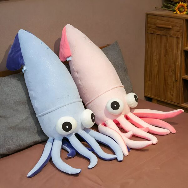Deux peluches de calmar, l'une bleue et l'autre rose, sont disposées sur un lit. Elles ont de grands yeux noirs et des tentacules moelleux.