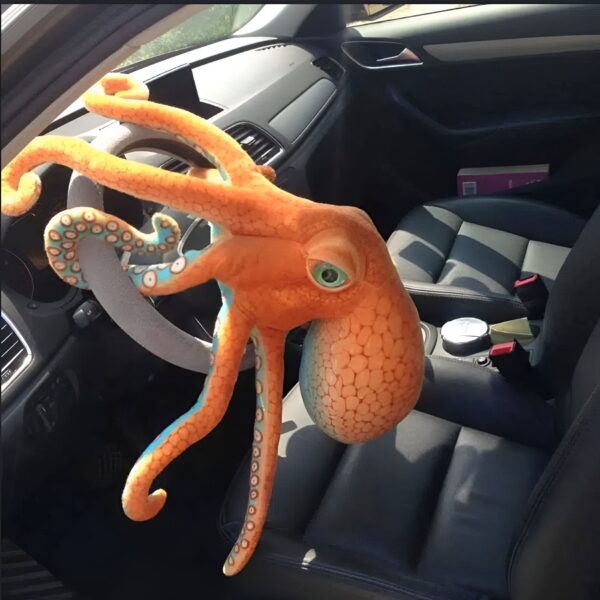 Une pieuvre en peluche orange et bleue est accrochée au volant d'une voiture.