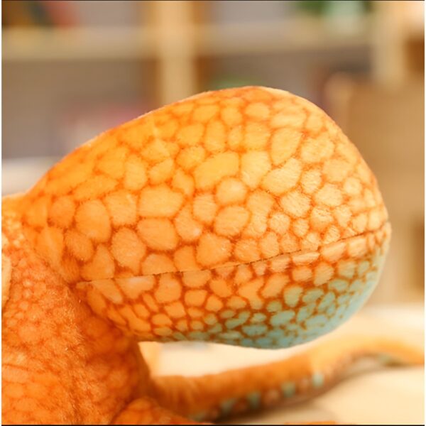 Gros plan sur la tête d'une peluche de poulpe orange et bleue. La texture est douce et réaliste.