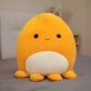 peluche-pieuvre-oreiller-doux-7a-5 Une peluche jaune en forme de pieuvre souriante avec des yeux noirs et une petite bouche. Elle a un ventre blanc et six tentacules jaunes.