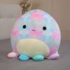 peluche-pieuvre-oreiller-doux-9a-1 Une peluche en forme de pieuvre avec un motif tie-dye coloré, des yeux noirs, un sourire et des tentacules de différentes couleurs.