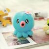 Une peluche de pieuvre bleue avec une fleur rose sur la tête.