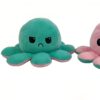 peluche-pieuvre-reversible-emoji-heureux-en-colere-cadeau-enfant-2a Une pieuvre en peluche de couleur turquoise avec un visage triste et des yeux noirs, sur fond blanc.