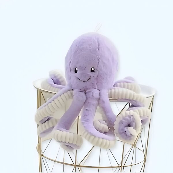 Une peluche de poulpe violette avec un visage souriant, assise sur un tabouret en métal doré.