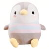 Une peluche de manchot gris avec un ventre rayé rose et bleu, assise sur un fond blanc.