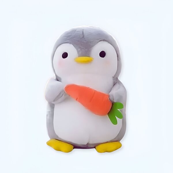 Un adorable pingouin en peluche tenant une carotte dans ses pattes.