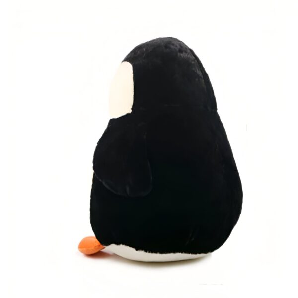 Une peluche de pingouin noire et blanche avec un bec orange, vue de côté.