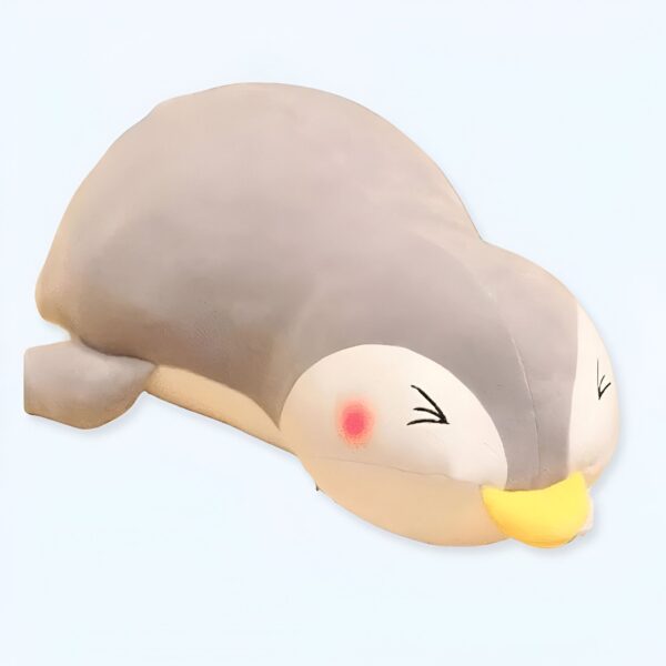 Un adorable peluche de pingouin gris avec un bec jaune et des joues roses, couché sur le ventre.
