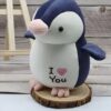 Un adorable manchot en peluche blanc et bleu avec un cœur rose sur le ventre et l'inscription "Je t'aime".