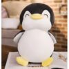 Une peluche de pingouin souriante avec un corps blanc, une tête noire et un bec jaune.