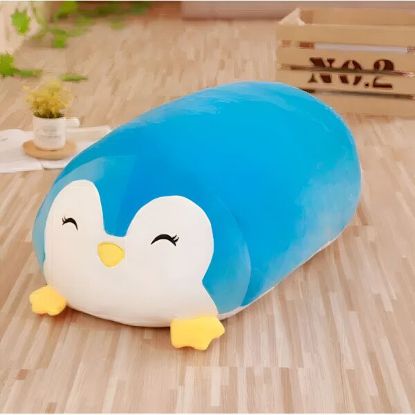Un coussin en forme de pingouin bleu avec des yeux souriants et un bec jaune.
