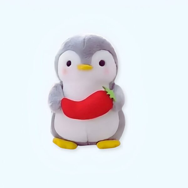 Peluche de pingouin gris tenant une carotte rouge.