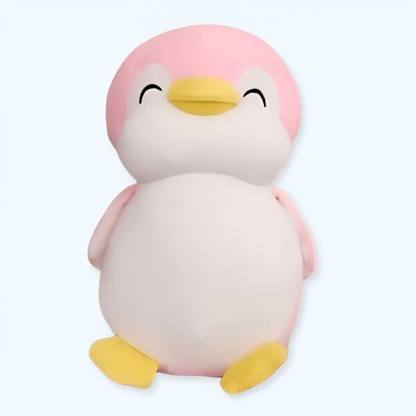 Une peluche de pingouin rose souriant avec des pattes jaunes.